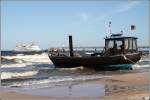 Ein Fischerboot liegt bei Bansin am Strand von Usedom. Im Hintergrund legt die ADLER DANIA an der Seebrcke von Bansin an. Die ADLER DANIA ist 53,60 m lang, 10,10 m breit und kann bis zu 670 Fahrgste befrdern. Aufnahmedatum 31.08.2005